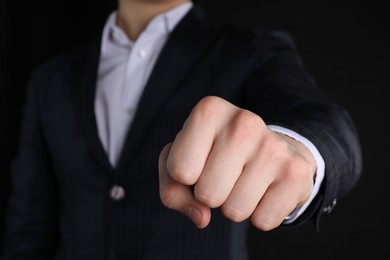 Photo of Businessman showing fist with space for tattoo on black background, closeup