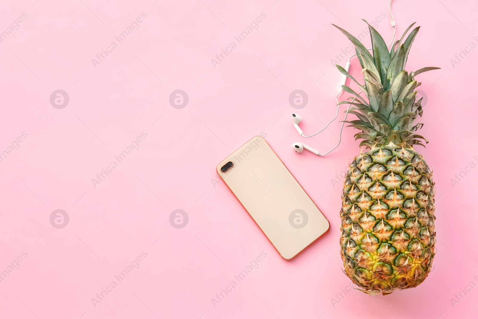 Photo of Fresh ripe pineapple with earphones and mobile phone on color background, top view