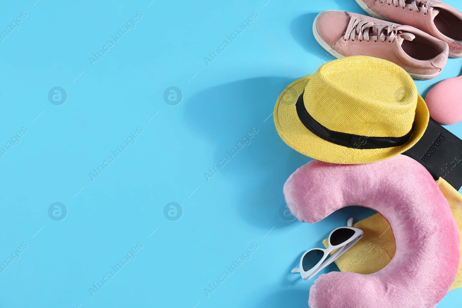 Photo of Flat lay composition with travel pillow and tourist stuff on light blue background. Space for text