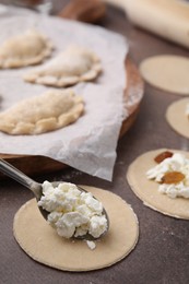 Photo of Process of making dumplings (varenyky) with cottage cheese. Raw dough and ingredients on brown table, closeup