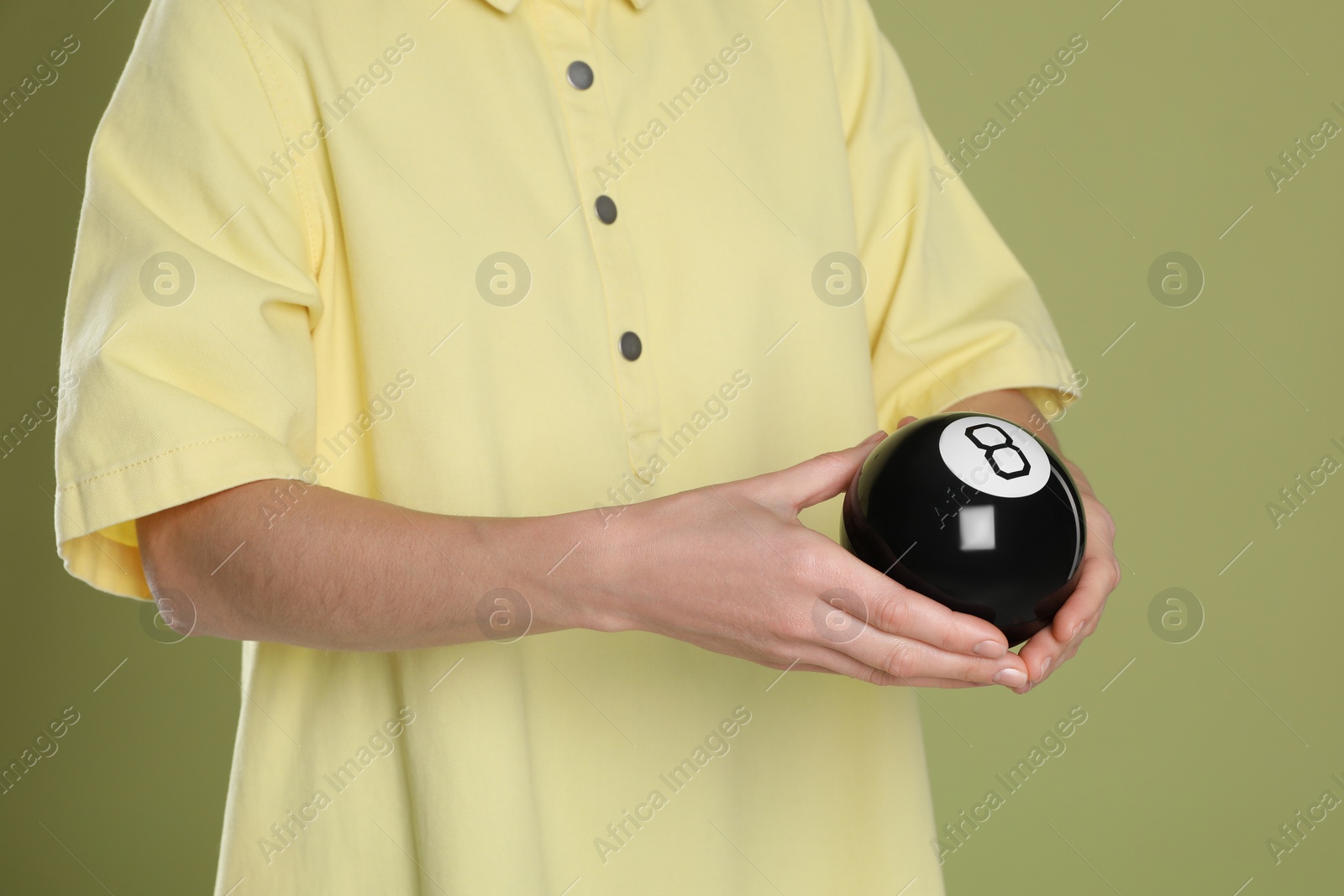 Photo of Man holding magic eight ball on olive background, closeup