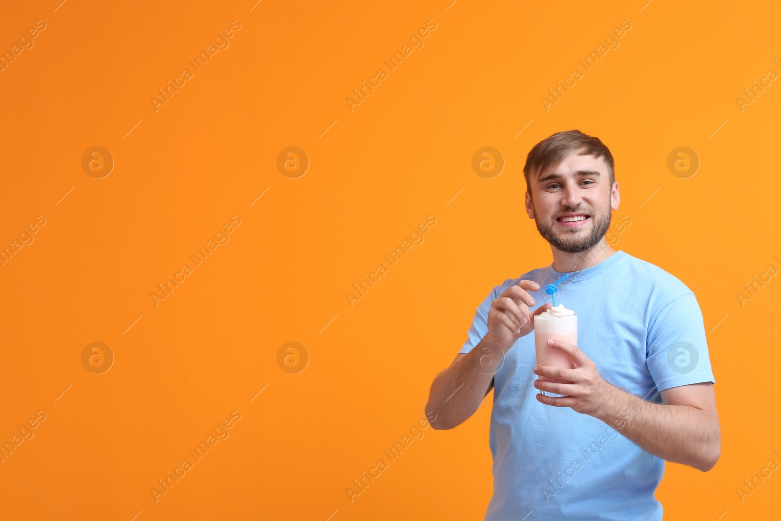 Photo of Young man with glass of delicious milk shake on color background