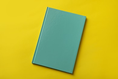 New stylish planner with hard cover on yellow background, top view