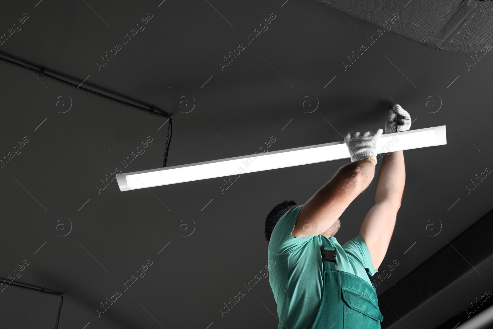 Photo of Ceiling light. Electrician installing led linear lamp indoors. Space for text