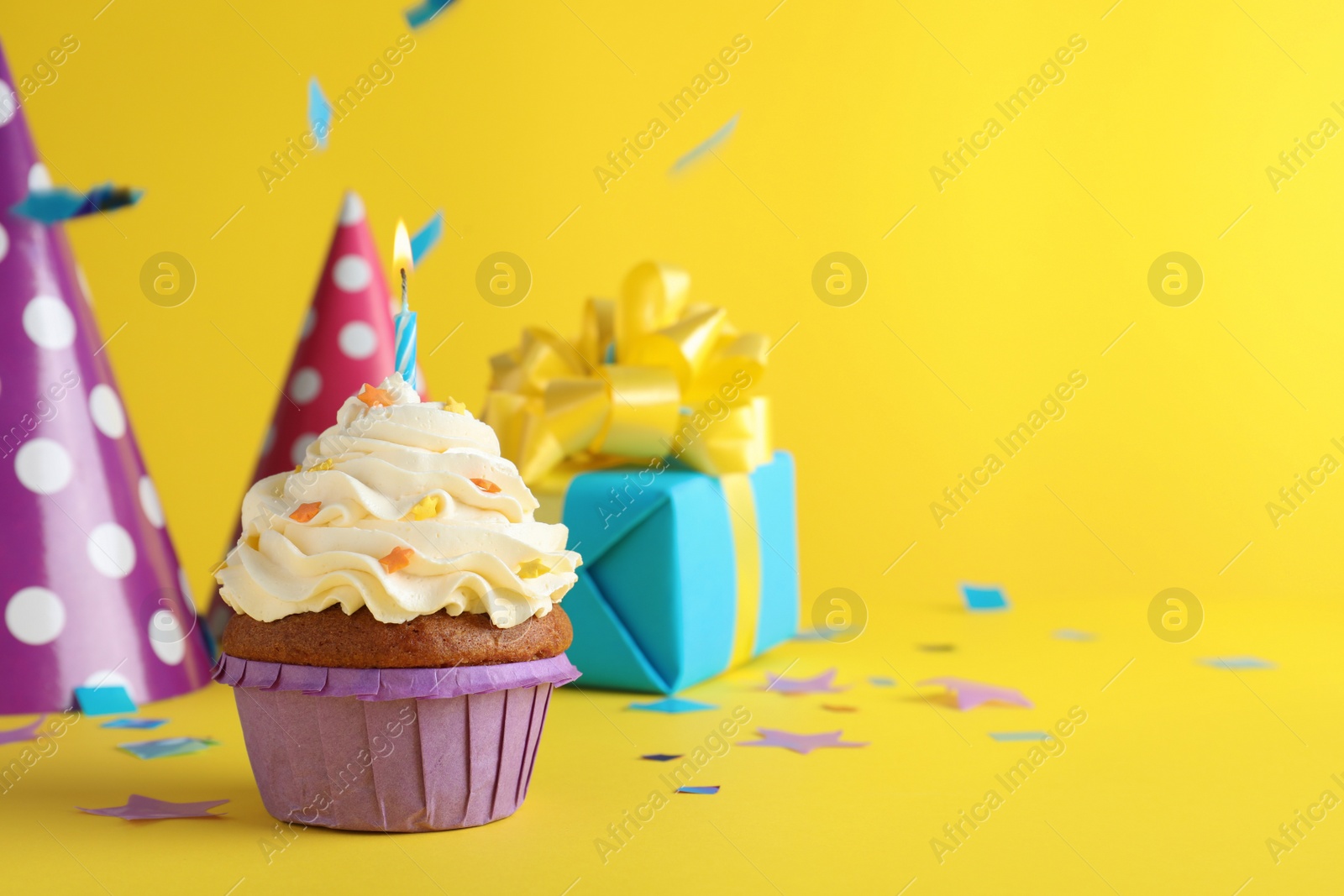 Photo of Delicious birthday cupcake with candle on yellow background, space for text