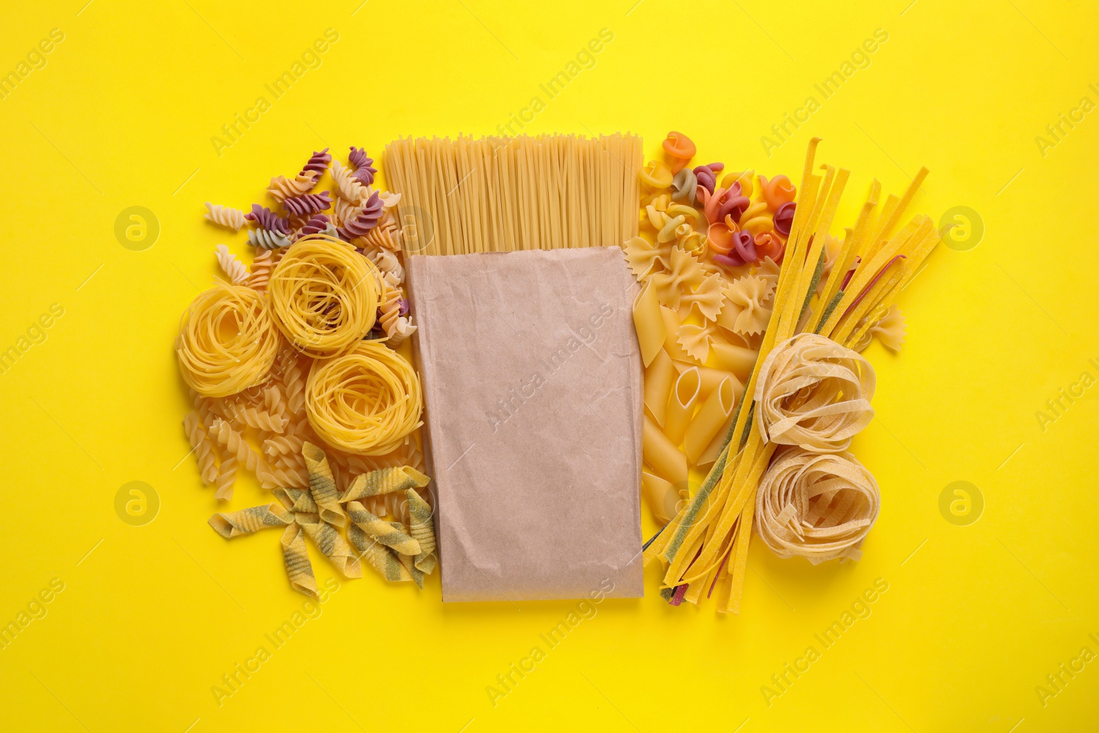 Photo of Different types of pasta on yellow background, flat lay