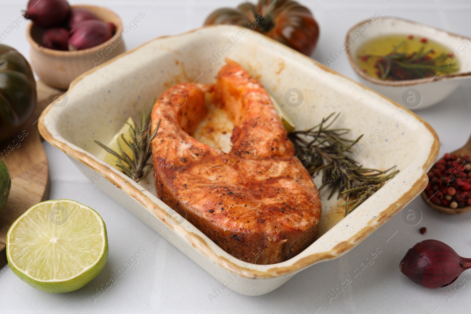 Photo of Freshly cooked fish and other products on white tiled table, closeup