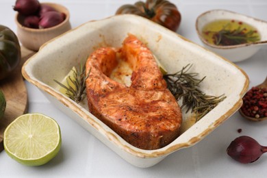 Photo of Freshly cooked fish and other products on white tiled table, closeup