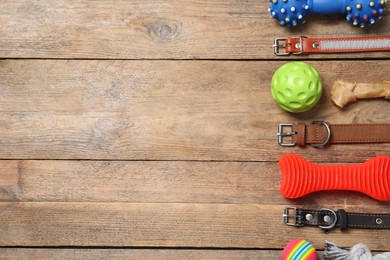 Photo of Flat lay composition with dog collars and toys on wooden table. Space for text