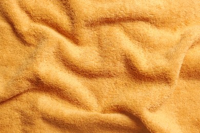 Photo of Soft crumpled orange towel as background, top view
