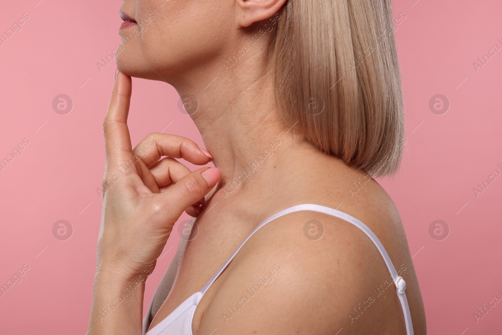 Photo of Woman touching her neck on pink background, closeup