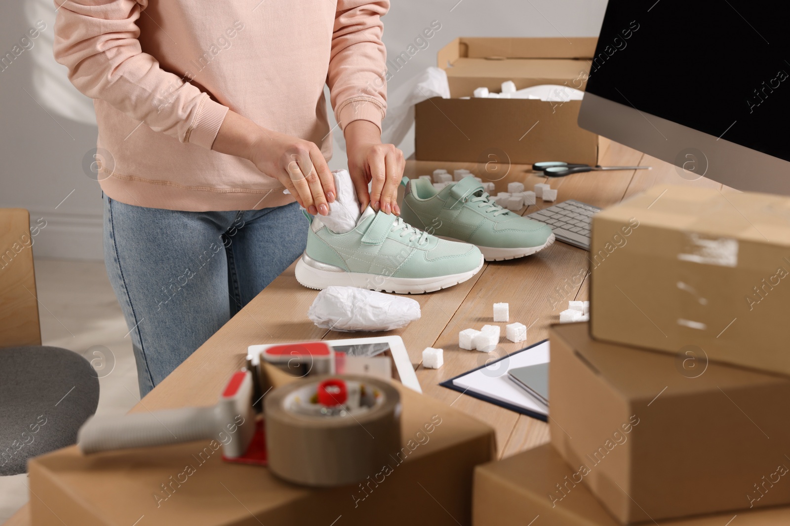 Photo of Seller packing shoes at workplace, closeup. Online store