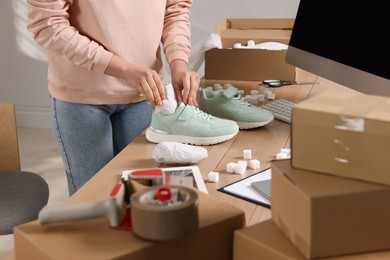 Photo of Seller packing shoes at workplace, closeup. Online store