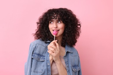 Beautiful woman with lollipop on pink background