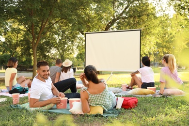 Photo of Young people with popcorn watching movie in open air cinema. Space for text