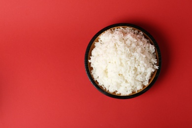 Photo of Bowl of boiled rice on color background, top view with space for text