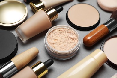 Photo of Face powders and other makeup products on grey background, closeup