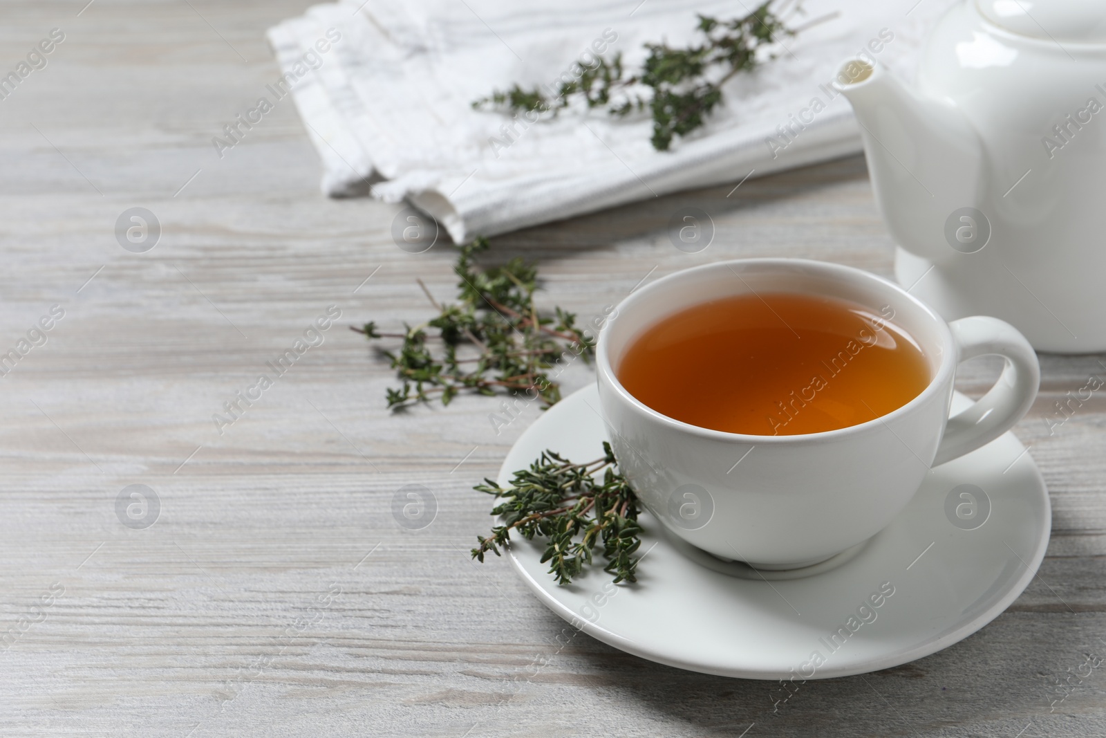 Photo of Aromatic herbal tea with thyme on white wooden table, space for text