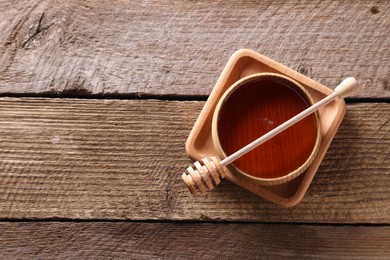 Photo of Delicious honey in bowl and dipper on wooden table, top view. Space for text