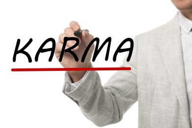 Man writing word KARMA on glass against white background, closeup