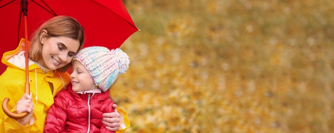 Image of Mother and daughter with umbrella in autumn park on rainy day, space for text. Banner design