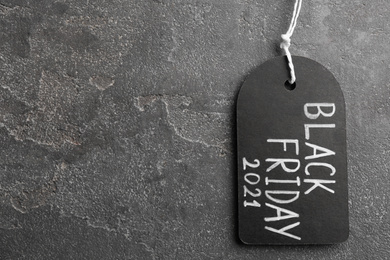 Photo of Top view of tag with words BLACK FRIDAY 2021 on grey stone background, space for text