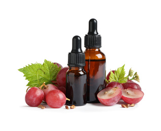 Photo of Organic red grapes, seeds and bottles of natural essential oil on white background