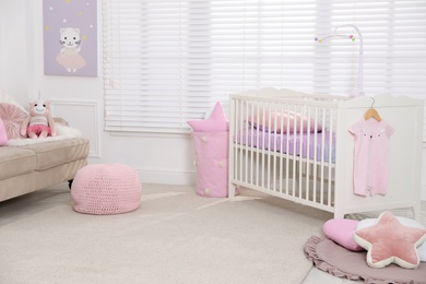 Photo of Cozy baby room with crib and sofa. Interior design
