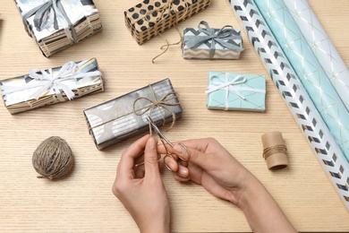 Woman decorating gift box on wooden background, top view