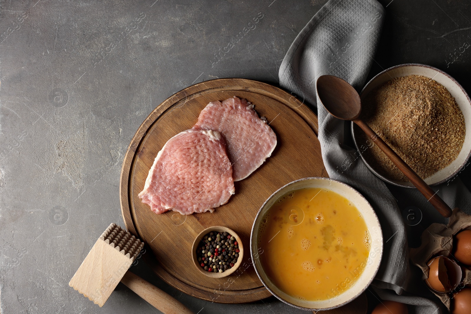 Photo of Ingredients for cooking schnitzel and meat tenderizer on grey textured table, flat lay. Space for text