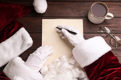 Photo of Top view of Santa writing letter at wooden table, closeup