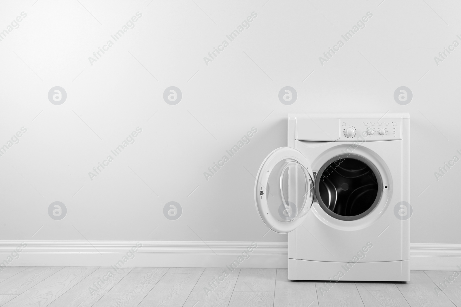 Photo of Modern washing machine near white wall, space for text. Laundry day