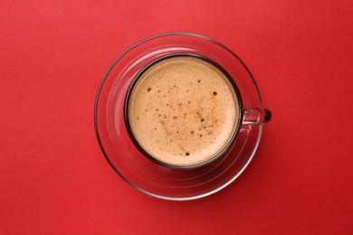 Photo of Fresh coffee in cup on red background, top view