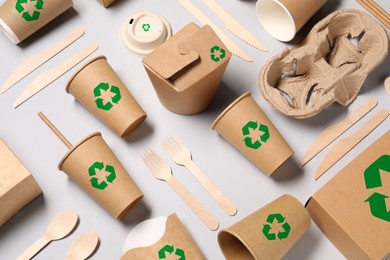 Image of Set of eco friendly food packaging with recycling symbols on light background, flat lay