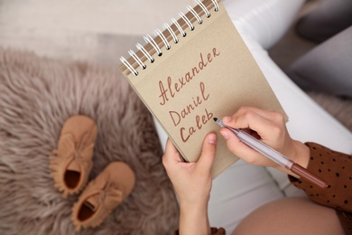 Pregnant woman writing baby names list, closeup