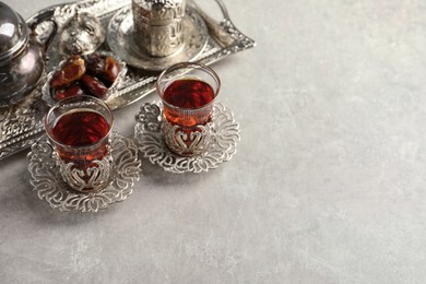 Photo of Tea and date fruits served in vintage tea set on grey table, space for text
