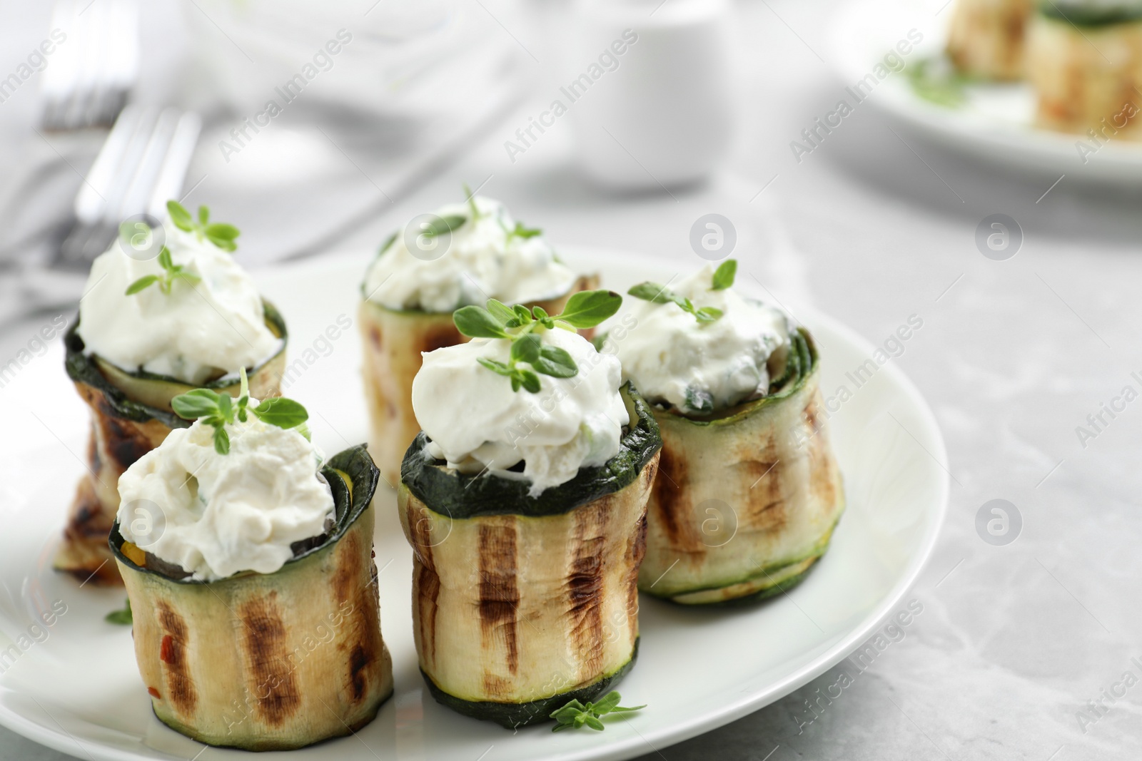 Photo of Stuffed zucchini rolls on grey marble table, closeup