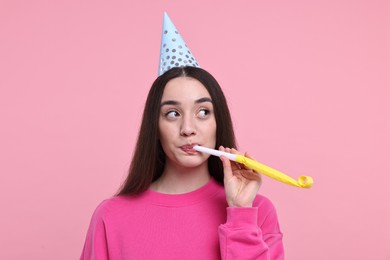 Photo of Woman in party hat with blower on pink background