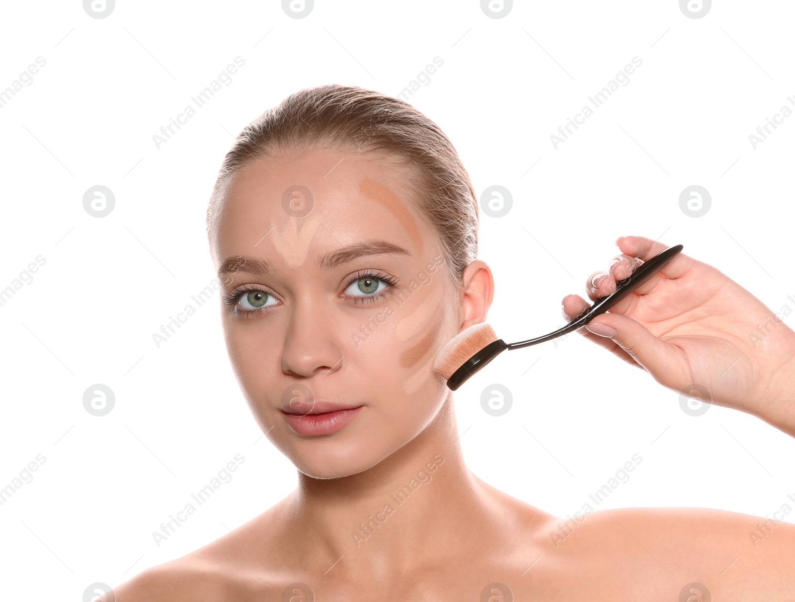 Photo of Young woman applying foundation on her face against white background