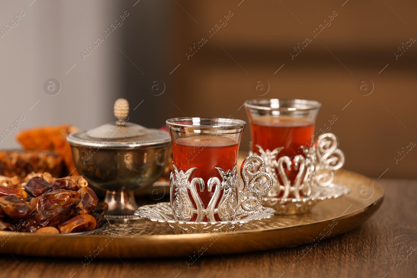 Photo of Glasses with tasty Turkish tea and oriental sweets on wooden table indoors, space for text