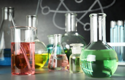 Photo of Laboratory glassware on table near chalkboard. Chemistry concept