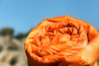 Photo of Orange sleeping bag on blurred background. Camping equipment