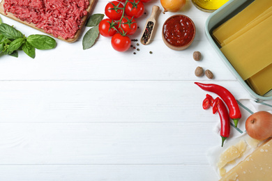 Fresh lasagna ingredients on white wooden table, flat lay. Space for text