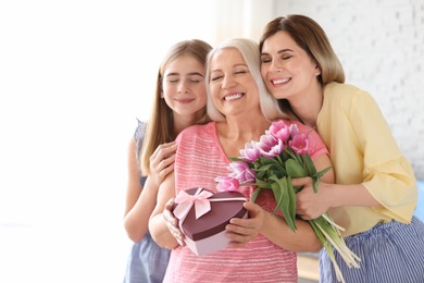 Young woman with daughter congratulating mature family member at home. Happy Mother's Day