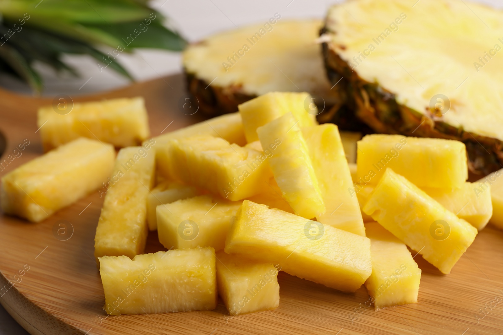 Photo of Pieces of tasty ripe pineapple on wooden board, closeup