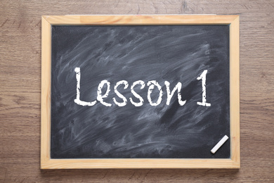 Image of Blackboard with phrase LESSON 1 on wooden background, top view