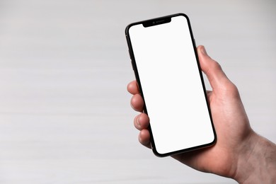 Photo of Man holding smartphone with blank screen on white background, closeup. Mockup for design