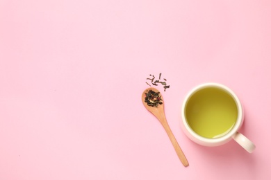 Photo of Spoon with green tea leaves and cup of hot beverage on pink background, flat lay. Space for text