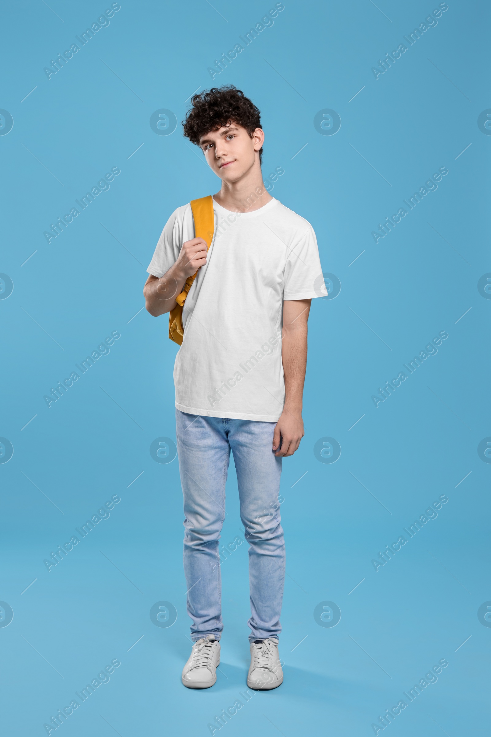 Photo of Teenage boy with backpack on light blue background