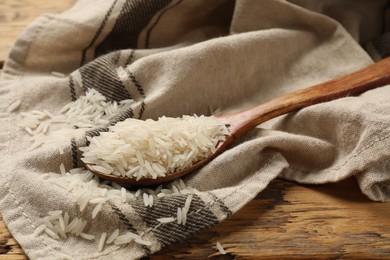 Photo of Raw basmati rice in spoon on wooden table, closeup